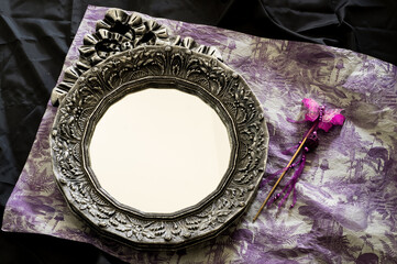 Still life with a vintage mirror and an ornament in violet and black tones, Halloween and Day of...