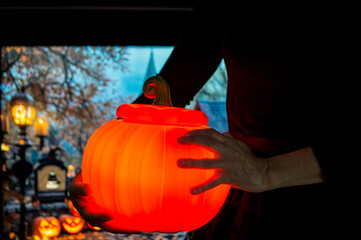 Gothic girl showing a lit pumpkin on Halloween