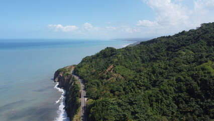 Fototapeta premium Aerial view drone Sea ocean waves blue sky rocks trees, mountains road Palomino, La Guajira, Colombia 4k