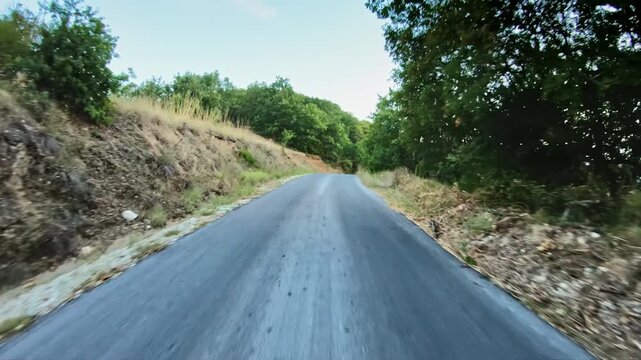 POV car drive on narrow asphalt mountain road, dry grass, trees, sunlight