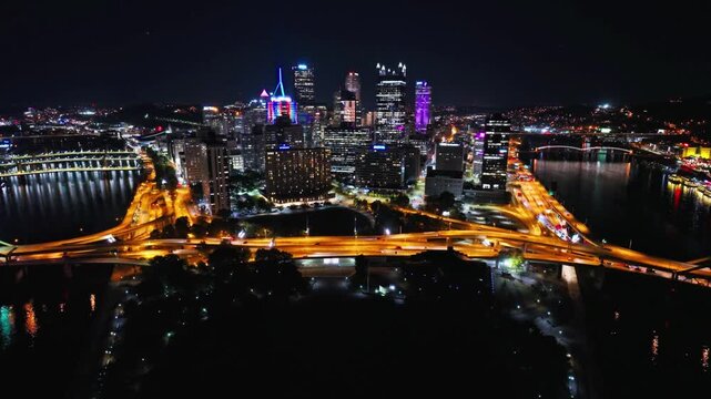 The city of pittsburgh glows brightly at night with lights reflecting in the river