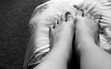 Black and white photo of bare feet resting on a patterned blanket, minimalistic composition, intimate and cozy atmosphere, suitable for themes of rest, mindfulness, or relaxation