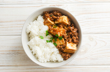 Mapo tofu dish in spicy sauce with minced beef in a ceramic bowl on a white background. Dish from Sichuan province. Traditional Asian food concept. Selective focus. Horizontal orientation. Top view.