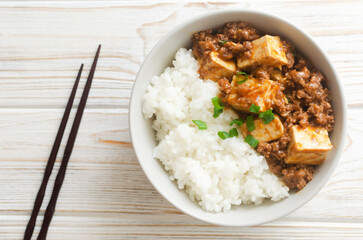 Mapo tofu dish in spicy sauce with minced beef in a ceramic bowl on a white background. Dish from Sichuan province. Traditional Asian food concept. Selective focus. Horizontal orientation. Top view.