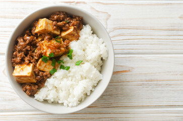 Mapo tofu dish in spicy sauce with minced beef in a ceramic bowl on a white background. Dish from Sichuan province. Traditional Asian food concept. Selective focus. Horizontal orientation. Top view.
