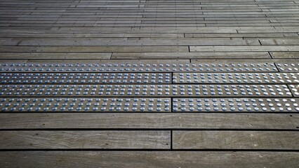 Special paving for the visually impaired on a wooden surface.