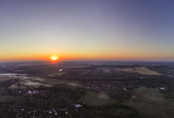 Aerial vibrant sunrise above rural farmlands and villages in summer morning scenery