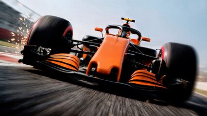 Front view of orange Formula 1 race car at high speed with sparks flying on track.