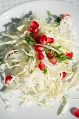 Closeup cabbage and pomegranate salad on white plate top view
