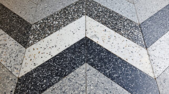 Terrazzo chevron pattern floor with abstract geometric texture, featuring grey, white, and black tiles creating a modern and decorative background surface