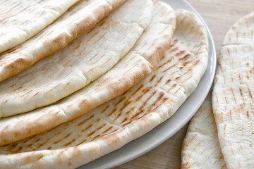 Pile of naan bread on a plate.