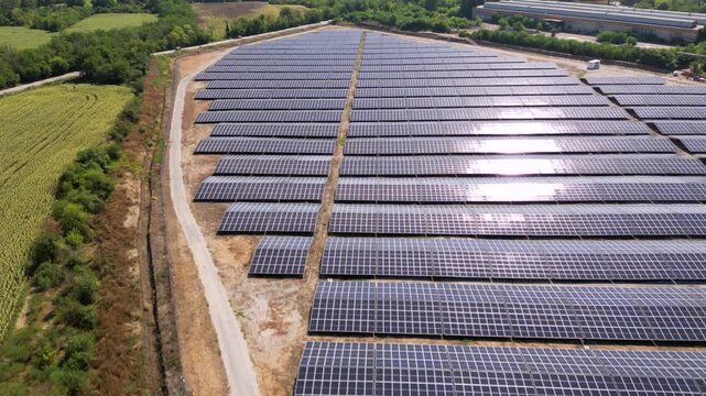 Drone view of expansive photovoltaic solar panel installation in rural agricultural area, renewable electricity generation plant supplying sustainable green energy for environmental protection and cli