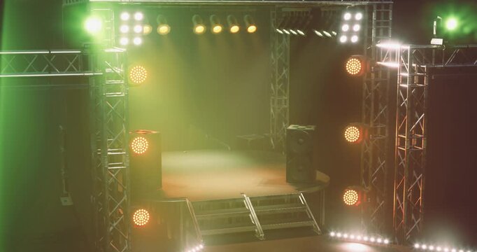 A vibrant concert stage is illuminated with colorful lights, showcasing speaker stacks on either side, waiting for performers to captivate the audience in an energetic atmosphere.