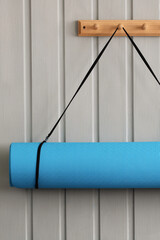 Blue yoga mat hanging on wooden wall rack