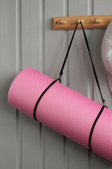 Pink yoga mat hanging on wooden wall hook