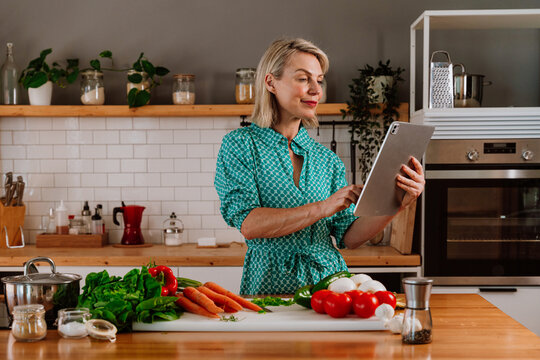 Woman using digital tablet while preparing ingredients in kitchen