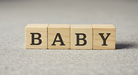 Wooden alphabet blocks spelling out the word BABY on a textured gray surface.