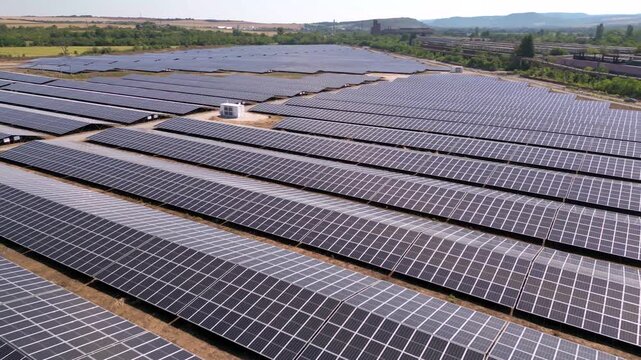Drone view of expansive photovoltaic solar panel installation in rural agricultural area, renewable electricity generation plant supplying sustainable green energy for environmental protection and cli