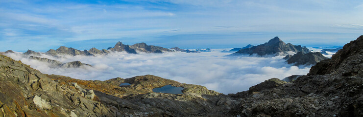 Panorama of Alps mountains on a sunny day. High resolution widescreen panorama of mountain landscape. Blue sky with some clouds above beautiful summits alpine range