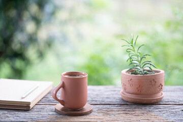 Earthenware brown clay coffee cup and clay potted plant, natural garden view background