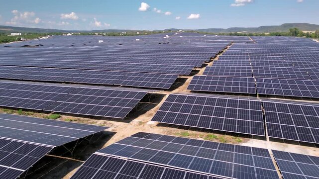 Drone view of expansive photovoltaic solar panel installation in rural agricultural area, renewable electricity generation plant supplying sustainable green energy for environmental protection and cli