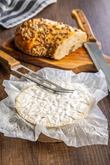 Camembert cheese on wrapping paper. French cheese with mold on the surface.