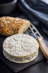 Camembert cheese on black table. French cheese with mold on the surface.