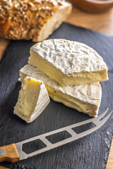 Camembert cheese on cutting board. French cheese with mold on the surface.