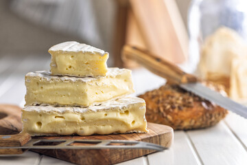 Camembert cheese on wooden cutting board. French cheese with mold on the surface.