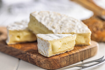 Camembert cheese on wooden cutting board. French cheese with mold on the surface.