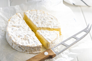 Camembert cheese on wrapping paper. French cheese with mold on the surface.