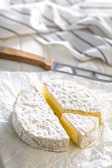 Camembert cheese on wrapping paper. French cheese with mold on the surface.
