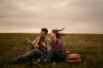Hikers resting on meadow and using smartphone