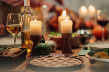 Festive thanksgiving table setting with candles, pie, and wine
