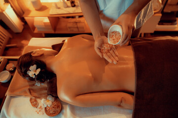 Woman customer having exfoliation treatment in luxury spa salon with warmth candle light ambient. Salt scrub beauty treatment in Health spa body scrub. Quiescent