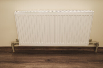 
White metal radiator mounted on the wall of a modern home interior. Heating equipment provides warm temperature and comfort during cold winter days.