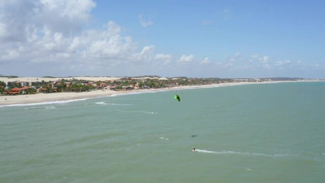 Kitesurfer glides across the turquoise water on a sunny day near the beach