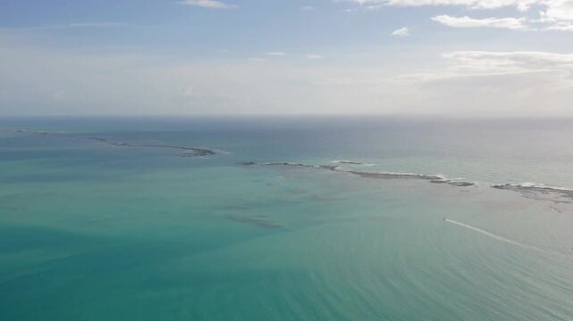 Aerial view of the turquoise ocean with a boat sailing on the horizon