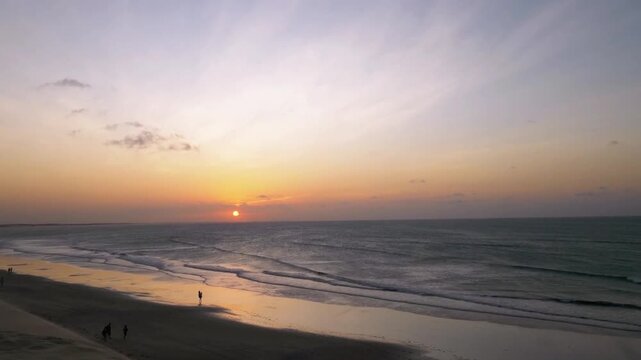 The sun sets over the ocean, casting a golden glow on the beach