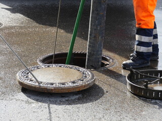 Man in an orange jumpsuit is working on a sewer pipe