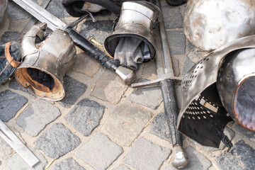 Medieval armor pieces and swords on cobblestone ground