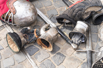 Medieval armor pieces and swords on cobblestone ground