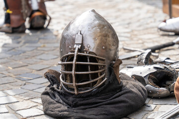 Medieval armor pieces and swords on cobblestone ground