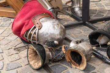 Medieval armor pieces and swords on cobblestone ground