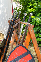 Medieval swords displayed on wooden rack at reenactment event