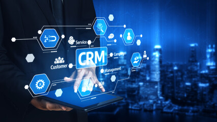 A business professional interacts with a tablet displaying a customer relationship management interface, showcasing digital tools over a city skyline at night. Tessel