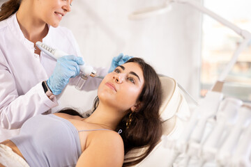 Young brunette woman having beauty procedure with macro molecule atomizing pen