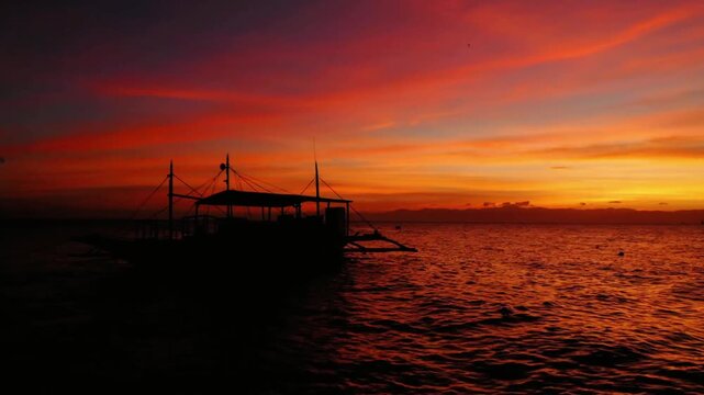 Silhouette of a boat on the ocean during a vibrant and colorful sunset