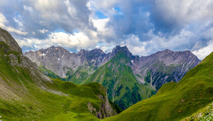 Fototapeta premium Panorama of Alps mountains on a sunny day. High resolution widescreen panorama of mountain landscape. Blue sky with some clouds above beautiful summits alpine range