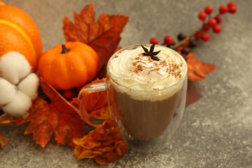 Warm drink topped with cream and spices surrounded by autumn decorations for cozy vibes